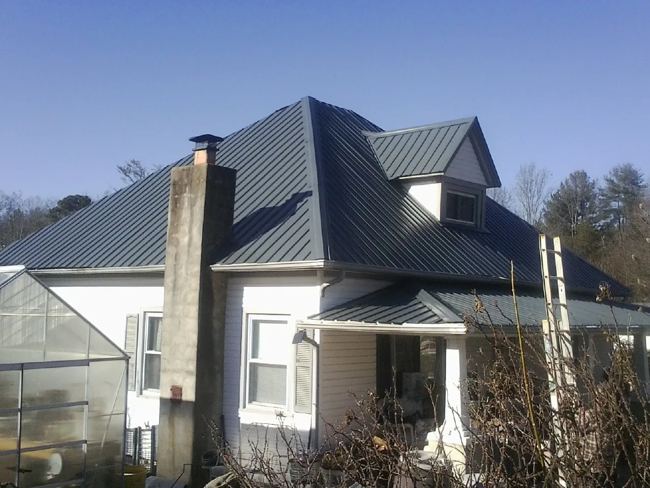 Dark blue standing seam metal roof on a white farmhouse with dormer — Slate & Tile Roof Repair by Roofing Brothers in Redding