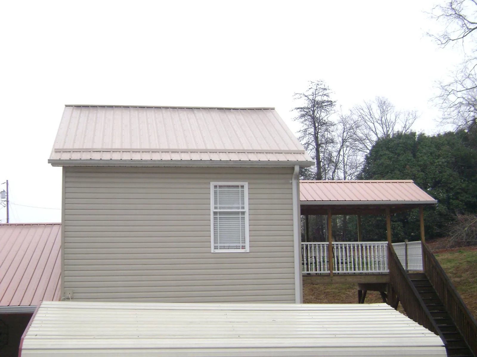 Tan metal roofs on a two story addition and attached porch, from a Roof Replacement job in Redding